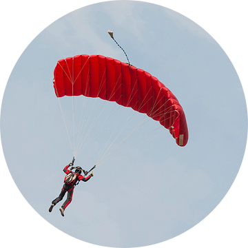 Parachutist aan een rode parachute tegen een blauwe lucht van Tonko Oosterink