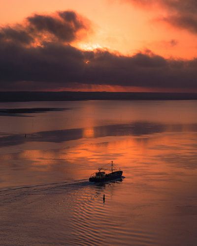 Een vissersboot vaart rustig over het spiegelende water