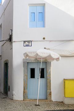 Wit Portugees huis met blauwe deuren en een parasol in Olhão, Algarve van Annette Hagemeijer