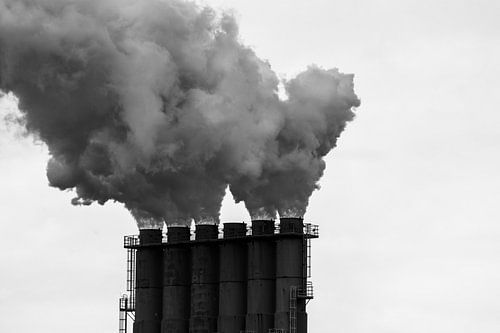 Dampende schoorstenen tegen een grijze wolkenlucht.