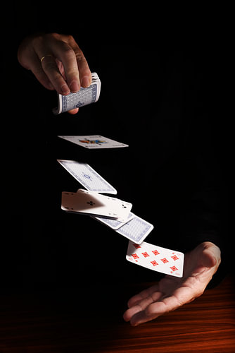 Werfen von Karten von einer Hand in die andere vor einem schwarzen Hintergrund mit Kopierraum, Gesch