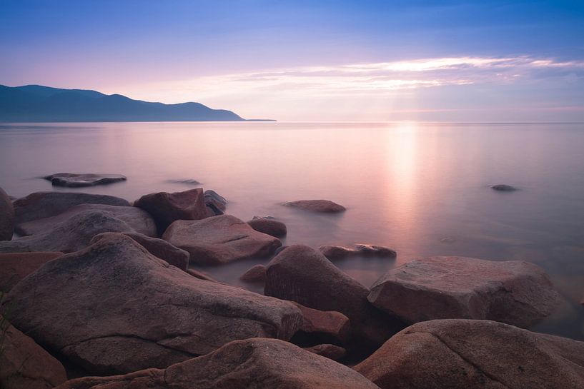 Zacht roze dageraad onder een blauwe hemel nabij roze stenen op een zomers Baikalmeer in Russisch Si van Michael Semenov