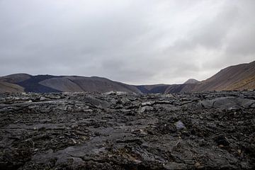 Lava aus der Nähe mit Vulkan im Hintergrund in Island | Reisefotografie von Kelsey van den Bosch