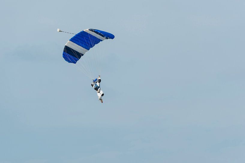 Parachutist aan een blauwe parachute tegen een licht blauwe achtergrond von Tonko Oosterink