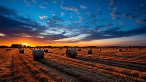 Sonnenuntergang über dem Feld mit Heuballen und dramatischem Himmel