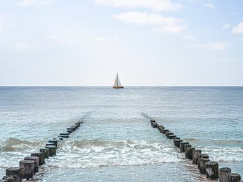 Segelboot zwischen Strandpfählen in Zoutelande, Zeeland