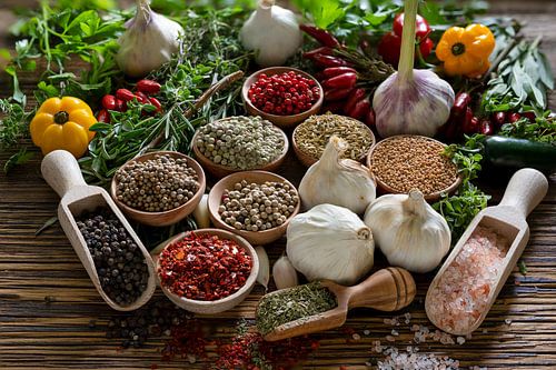 Natuurlijke keukenkruiden in schaaltjes op een houten plank