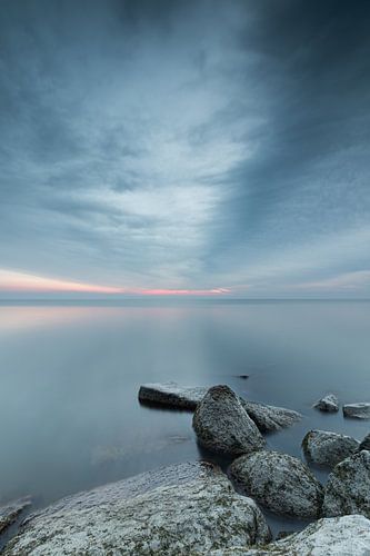 Stenen in het water van het Markermeer bij een bewolkte zonsopkomst