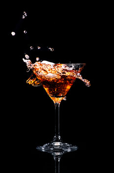 Ein spritzender Cocktail in einem Martini-Glas vor schwarzem Hintergrund