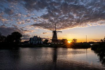 Zonsondergang met Nederlandse windmolen in de wateren van Kralingse Plas, Rotterdam, Nederland