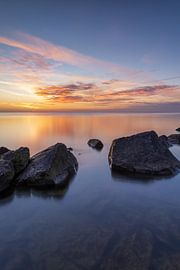 Sonnenaufgang über dem IJsselmeer bei Den Oever mit Steinen im Vordergrund von Bram Lubbers