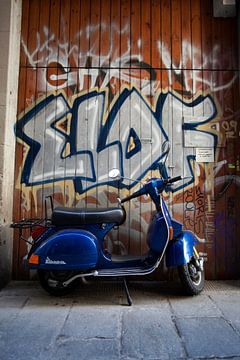 Scooter bleu dans une ruelle de la vieille ville avec des graffitis sur un mur en bois à Barcelone,  sur WorldWidePhotoWeb