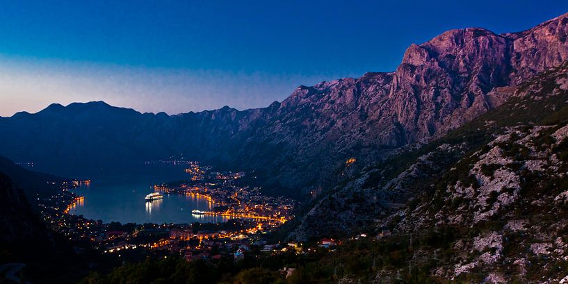 Cruiseschip ver beneden in de baai tussen de bergen bij de stad, tropische nacht. Montenegro Kotor B van Michael Semenov