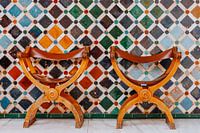 Two authentic chairs in front of a mosaic wall