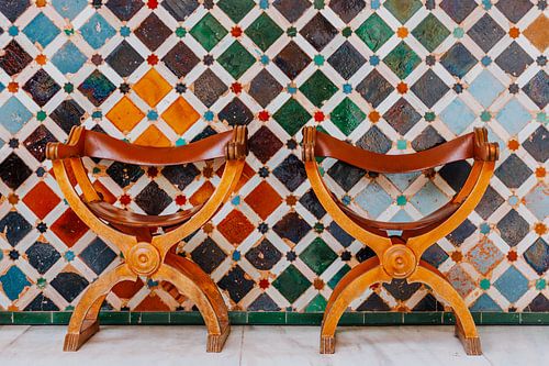 Two authentic chairs in front of a mosaic wall