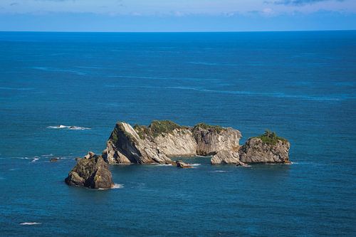 Rotsen in diepblauw water in Nieuw-Zeeland
