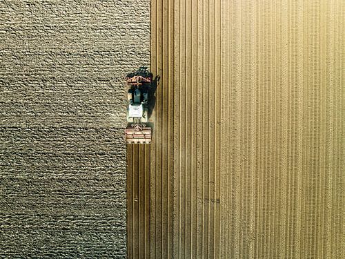 Tractor maakt de grond klaar voor het planten van gewassen van bovenaf gezien