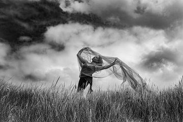 Femme dansant dans l'herbe de la plage par un jour nuageux. sur Corine de Ruiter