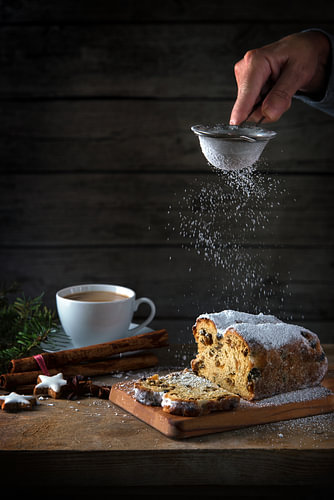 Weihnachtskuchen, in Deutschland wird der Christstollen auf einem rustikalen Holztisch mit Puderzuck