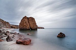 Strand mit rötlichen Steinblöcken, Wasser- und Wolkenbewegung
