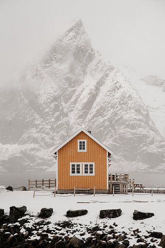 Gelbes Haus unter verschneiten Berggipfeln in Norwegen