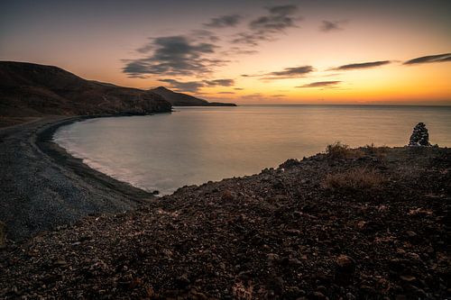 Fuerteventura, zonsopgang op een stenen strand met uitzicht over de baai naar de zee