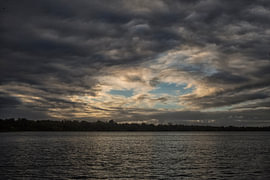 Sunset and clouds over the river by Patricia Hofmeester