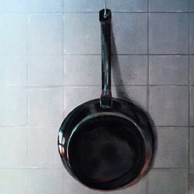 Frying pan hanging on kitchen wall by Jan Brons