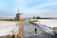 Ice skating in a Dutch polder landscape with view of a windmill.