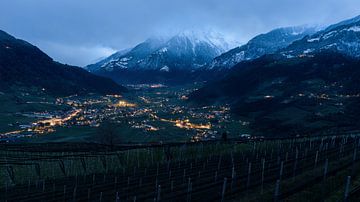 Bergtal am Abend mit Lichtern und Gipfeln im Schnee