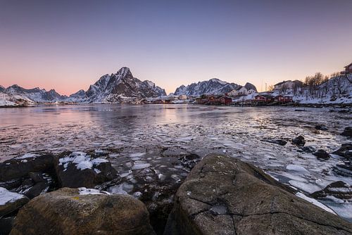 Schneebedeckte Berge und gefrorener Fjord im morgendlichen Sonnenlicht in Reine auf den Lofoten in N