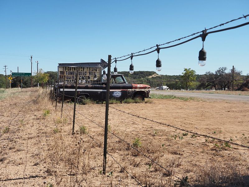 Roestige pickup truck als wegwijzer naar muzikale stad in Texas van Atelier Liesjes