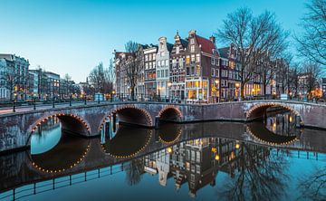 De prachtige Amsterdamse grachten tijden het blauwe uurtje. van Claudio Duarte