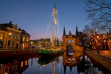 Versierde traditionele boot bij de waterpoort in Sneek in Nederland bij avond van Eye on You