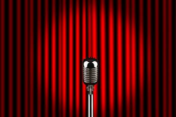 Un microphone sur une scène devant un rideau rouge