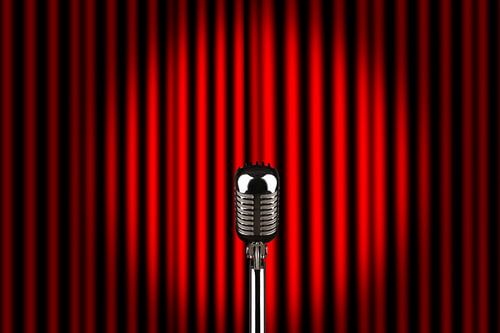 A microphone on a stage in front of red curtain