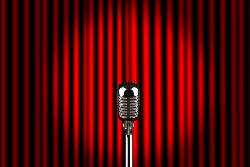 Ein Mikrofon auf einer Bühne vor rotem Vorhang von Jörg B. Schubert