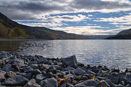Tranquil mountain lake with autumnal hills and rocks in the clear water