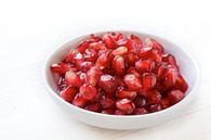 seeds of pomegranate in a small bowl on a white painted wooden background, closeup with selective fo by Maren Winter thumbnail