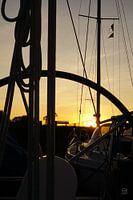 Steuerrad einer Segelyacht mit untergehender Sonne.