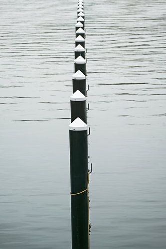 Row of black mooring piles or dolphins in the water, empty yacht