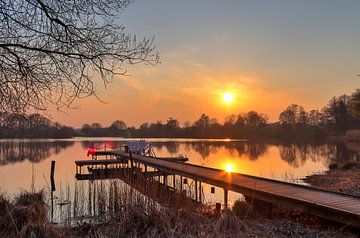 Kleine aanlegsteiger aan een meer met een oranjegele zonsondergang van MPfoto71
