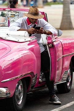 Mann mit Handy in rosa Oldtimer in Havanna von Dieter Walther