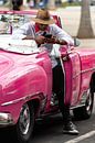 Un homme avec un téléphone portable dans une voiture ancienne rose à La Havane par Dieter Walther Aperçu