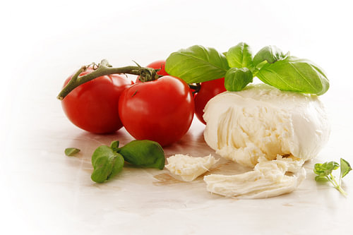 Italienischer Caprese, Mozzarella, Tomaten und Basilikumkraut auf einer hellen Marmorplatte, Kopierr