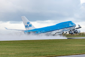 Eine Boeing 747-400 der KLM hebt von der nassen Polderbaan ab.