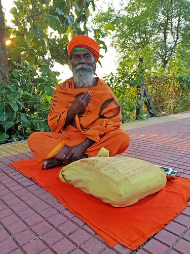 Sadhu in oranje kleding zittend op straat in Tiruvanamalai Tamil Nadu India