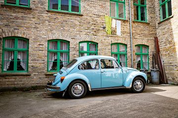 Retro blauwe klassieke auto geparkeerd naast bakstenen gebouw