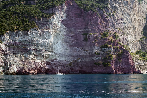 Kleines Segelboot in einer Bucht vor den Felsklippen des Mittelmeers, Kopierraum
