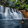 Tropical waterfall with local in yellow swimming trunks by Corrine Ponsen